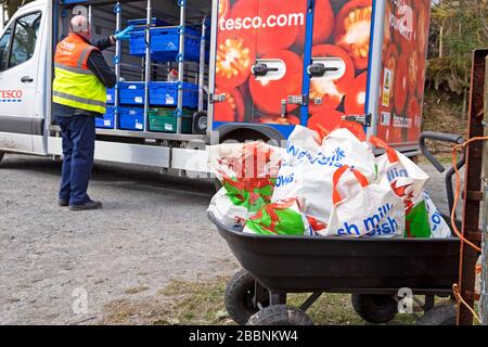 Tesco Supermarkt-Van-Fahrer, der während der Coronavirus Covid-19-Pandemie Wales UK 2020 Lebensmittel in Plastiktüten an das Kundenheim im ländlichen Wales liefert Stockfoto
