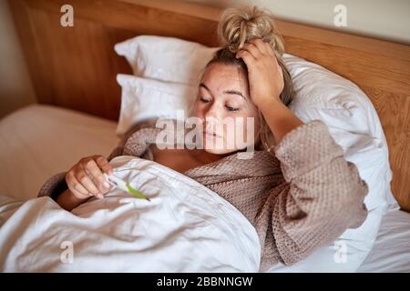 Ein einzelnes, blondes, kaukasisches Weibchen erkrankt im Bett mit einem saisonalen Virus Stockfoto