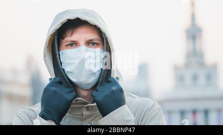 Nahaufnahme Portrait junger europäer Mann in schützender, medizinischer Gesichtsmaske, die draußen spazieren geht. Neues Coronavirus (COVID-19). Konzept der Gesundheitsversorgung Stockfoto