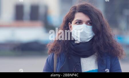 Nahaufnahme Portrait junge europäerin in schützender, medizinischer Gesichtsmaske, die draußen spazieren geht. Neues Coronavirus (COVID-19). Konzept des Gesundheitsautos Stockfoto