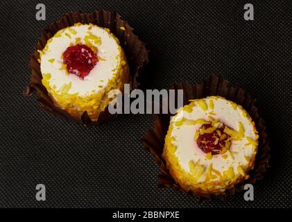 Weiße runde Kuchen in Papierverpackungen Nahaufnahme auf schwarzem Hintergrund Stockfoto
