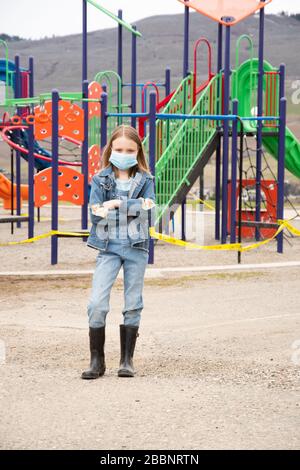 Das kanadische Mädchen trug eine Maske, die 2020 während einer Corona-Viruspandemik vor dem Spielplatz stand Stockfoto