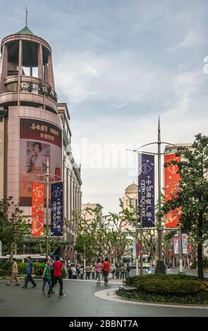 Shanghai, China - 4. Mai 2010: Belebtes Einkaufsviertel der Nanjing Road. CITIC-Platz mit grünen Bäumen, vielen Fußgängern, Bannern und Bauen Stockfoto