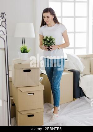 Fröhliche junge Frau, die in ihrer neuen Wohnung steht Stockfoto