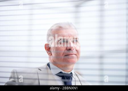 Bis zu schließen. nachdenklich Geschäftsmann Blick durch Fenster Jalousien Stockfoto