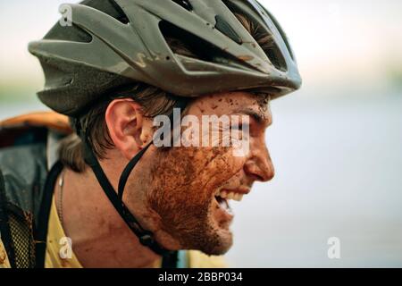 Glückliche junge Mountainbiker lachen als er in Schlamm bedeckt ist. Stockfoto