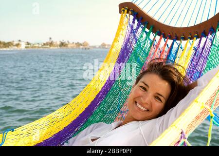 Porträt einer lächelnden Frau, die in einer Hängematte liegt. Stockfoto