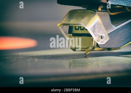 Der Eingabestift des analogen Vinylspielers steht in Kontakt mit der Oberfläche des rotierenden LP. Makro. Retro-Stil. Stockfoto