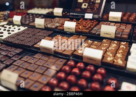 Auswahl an Schokoladenkäuzen Desserts im Café Showcase. Verschiedene Süßigkeiten mit verschiedenen Geschmacksrichtungen, Nüsse im Geschäft. Stockfoto