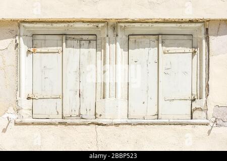 Fassade eines verlassenen, baufälligen Hauses mit 2 Fenstern mit Fensterläden Stockfoto