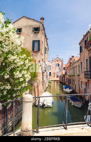 VENEDIG, ITALIEN - 15. JUNI 2017: Venetianischer Kanal mit Booten und Kirche Madonna dell'Orto in der Ferne. Bezirk Cannaregio in Venedig, Italien Stockfoto