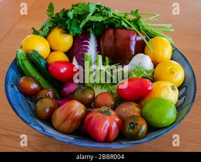 Bunte Schüssel mit frischem Obst und Gemüse: Chicoree, Petersiliekraut, Zwiebeln, Zucchini, Fenchel, Tomaten, Zitronen, Limetten, Pfeffer und Knoblauch Stockfoto