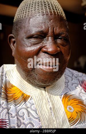 Porträt eines Yoruba-Mannes mittleren Alters, der mit traditionellem farbenfrohen Anzug mit traditionellen Yoruba-Narben auf seinem Gesicht bekleidet ist. Stockfoto