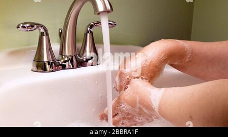 Foto einer Frau, die ihre Hände mit Seife und Wasser in einem Waschbecken waschen Stockfoto