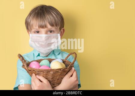 Covid easter Concept - Junge hält Korb mit ostereiern mit medizinischer Maske Stockfoto