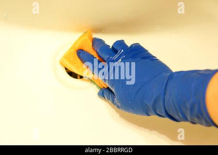 Mädchen mit blauen Gummihandschuhen und einem Schwamm reinigen das Badezimmer Stockfoto