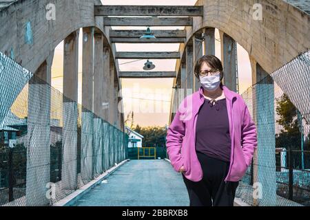 Ältere Frau in schützender medizinischer Maske isoliert gegen leere Straßen . Coronavirus älterer Rat. Sichere alte Männer. Übertragung des Virus auf Stockfoto