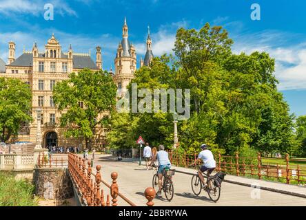 Schwerin - Juli 2018, Deutschland: Zwei Radfahrer auf dem Weg zum Schweriner Schloss, dem berühmtesten Wahrzeichen des Landes Mecklenburg-Vorpommern Stockfoto