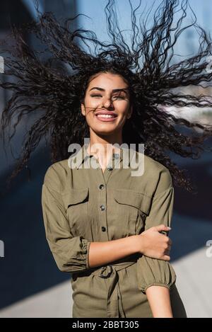 Junge attraktive Frau mit ihrem gewellten Haar im Wind lächelnd Stockfoto