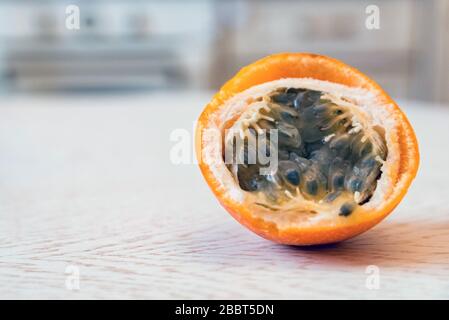 Schneiden Sie in einer Küche Granadilla- oder gelbe Passion- oder Granadiobst auf weißem Tisch Stockfoto