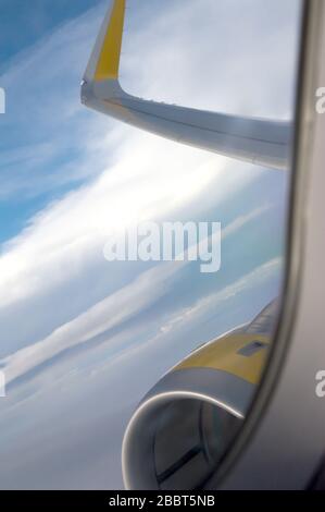 Blick auf einen Flugzeugflügel, den Himmel und seine Wolken aus dem Fenster eines kommerziellen Flugzeuges Stockfoto