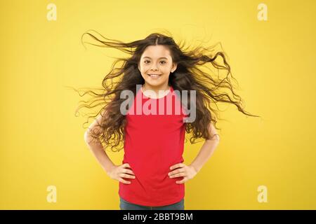 Kind süß Gesicht mit adorable curly Frisur. Kleines Mädchen lange Haare wachsen. Teen Mode Modell. Unterschied entdecken. Styling lockiges Haar. Friseur Tipp. Kind Mädchen lange gesund glänzendes Haar. Perfekte locken. Stockfoto