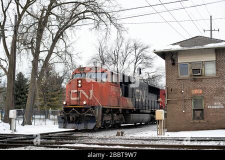 West Chicago, Illinois, USA. Ein Güterzug der Canadian National Railways, der einen Kontrollturm passiert, bevor er eine Kreuzung überquert. Stockfoto