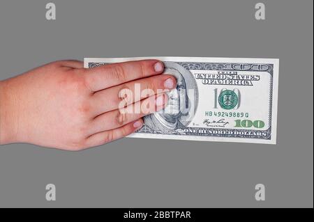 Man's Hand hält eine Banknote von 100 US-Dollar mit einem Porträt des amerikanischen Präsidenten Benjamin Franklinan isolierten grauen Hintergrund. Stockfoto