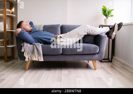 Porträt Des Müden Mannes, Der Auf Der Couch Schläft Stockfoto