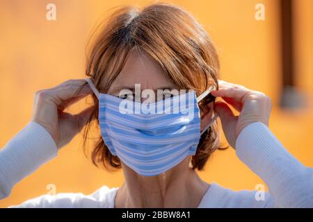 Frau, die eine Atemmaske trägt, selbstgenäht, aus Baumwolle, Auswirkungen der Koronakrise in Deutschland, Stockfoto