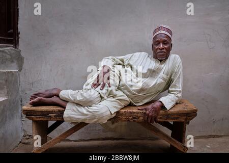 Porträt eines Nigerianers mittleren Alters, der auf einer Holzbank liegt. Stockfoto