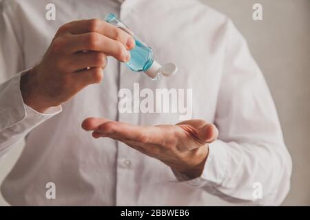 Mann in weißem Hemd mit Händedesinfektions-Gelspender, Coronavirus Covid-19 an öffentlichen Orten. Antiseptisches, hygienisches und medizinisches Konzept Stockfoto