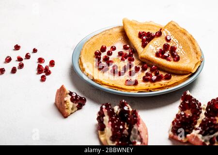 Pfannkuchen mit Granatapfel und Kondensmilch liegen auf einem Teller. Nahaufnahme. Stockfoto