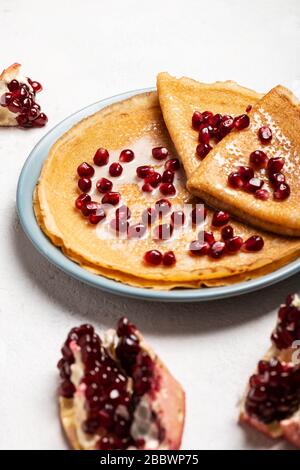 Pfannkuchen mit Granatapfel und Kondensmilch liegen auf einem Teller. Nahaufnahme. Stockfoto