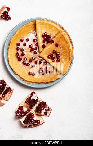 Pfannkuchen mit Granatapfel und Kondensmilch liegen auf einem Teller. Nahaufnahme. Platz für Text kopieren. Draufsicht. Stockfoto