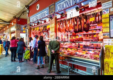 Menschen, die in einem Metzger- und DELI-Stall am Triana-Markt (Mercado de Triana), Sevilla, Andalusien, Spanien einkaufen Stockfoto