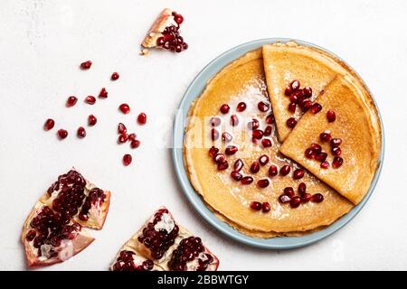 Pfannkuchen mit Granatapfel und Kondensmilch liegen auf einem Teller. Nahaufnahme. Draufsicht. Stockfoto