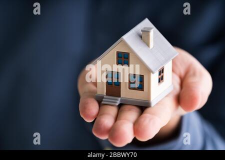 Midsection Of Businessman Holding House Model In Office Stockfoto