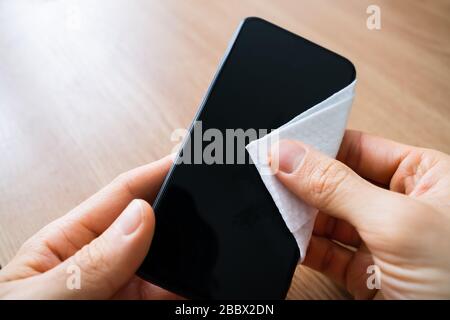 Man Wischt Den Bildschirm Des Mobiltelefons Mit Desinfektionsmittel Ab Stockfoto