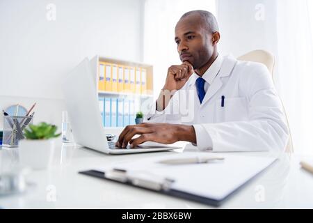 Foto der Familie Doc Dunkle Haut Kerl sehen Sie sich moderne Technologie Notebook Innovation medizinische cov virale Nachrichten Look Bildschirm online helfen tragen weißen Labormantel Stockfoto