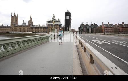 London, Großbritannien. April 2020. Tag Nine of Lockdown in London. Ein Läufer überquert die Westminster Bridge, die fast keinen Verkehr hat, da das Land aufgrund der COVID-19 Coronavirus Pandemie gesperrt ist. Die Menschen dürfen nicht nach Hause gehen, außer bei minimalem Lebensmitteleinkauf, medizinischer Behandlung, Bewegung - einmal am Tag und wesentlicher Arbeit. COVID-19 Coronavirus Lockdown, London, Großbritannien, am 1. April 2020 Credit: Paul Marriott/Alamy Live News Stockfoto