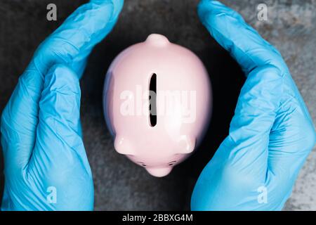 Hand In Handschuhe Schützen Piggybank Geld Sparen Vor Coronavirus Rezession Stockfoto