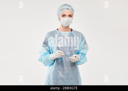 Weiblicher Arzt oder Chirurg in medizinischer Uniform und medizinischer Schutzmaske, die den Endotrachealtubus hält und auf weißem Grund posiert, isoliert Stockfoto