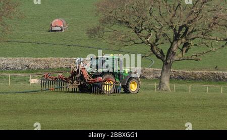 Ein Traktor auf einer Yorkshire Farm, der Schlagsaustrittsgeräte abschleppt. Stockfoto