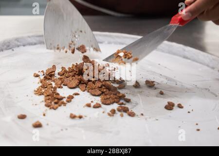 Der Konditor füllt Eis auf eine gekühlte Metalloberfläche. Stockfoto