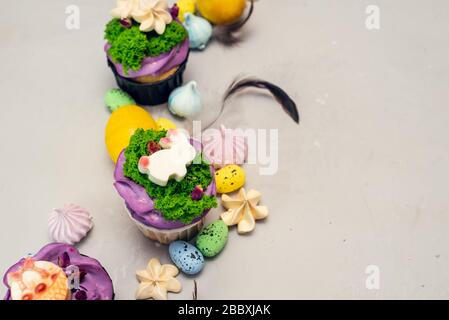 Orthodoxe Osterkuchen, die mit Sahne in Form von Gras und weißen Schokoladenfigurinen verziert sind. Osterhase Cupcakes, Ostern Essen Handwerksidee für Kinder. Stockfoto