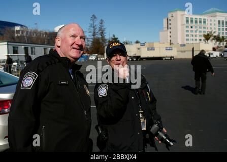 Der US-amerikanische Zoll- und Grenzpatrouillendirektor für den Außendienst von San Francisco und ein CBP-Offizier sehen sich auf die Annäherung an CBP-Flugzeuge aus, während sie im Vorfeld des Super Bowl 50 in Santa Clara, Kalifornien, 2016 an Sicherheitsoperationen teilnehmen. Stockfoto