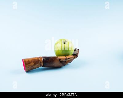 Frischer grüner apfel in der Palme aus Holzhand auf Blau Stockfoto