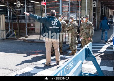 New York, USA. April 2020. Ein Mitarbeiter des Büros eines medizinischen Prüfers gibt einer Einheit von Mitgliedern der Nationalgarde in der East 3oth Street in der Nähe des Büros des Chefarztprüfers in New York City Anweisungen, während die Stadt sich auf einen Anstieg der COVID-19-Fälle vorbereitet, die eine medizinische Behandlung erfordern; April 2020 in New York, NY, USA statt. (Foto von Albin Lohr-Jones/Sipa USA) Credit: SIPA USA/Alamy Live News Stockfoto