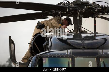 Ein Mitarbeiter der Luftinterdiktion beim US-amerikanischen Zoll- und Grenzschutz, der Luft- und Marineinfanteration überprüft das Getriebeöl eines UH-60 Black Hawk Hubschraubers vor einem Flug zur Luftraumsicherheit für Super Bowl LI in Conroe, Texas, 1. Februar 2017. Einheiten mit Air and Marine Operations und Office of Field Operations haben sich mit der Civil Air Patrol zusammengetan, um einen Luft-Luft-Abfangen mit zwei AMO UH-60 Black Hawk Hubschraubern und zwei C-550 Citation Jets zu üben, um einen simulierten Einfall in den eingeschränkten Luftraum aufzuspüren Stockfoto